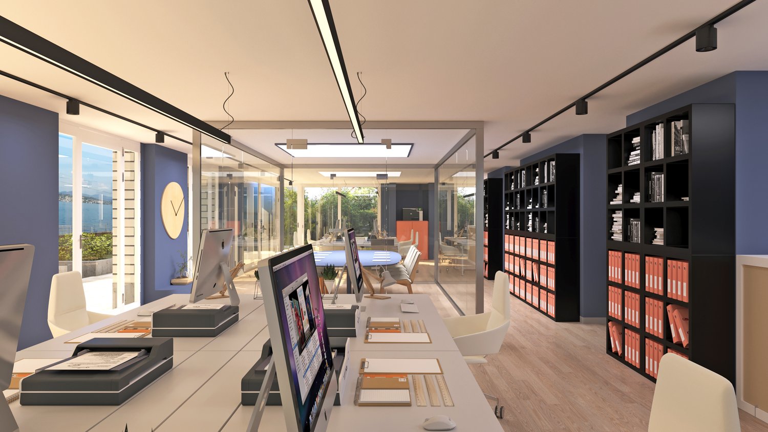 Open office with multiple desks, two computer screens on each desk, modern office chairs, bookshelves, glass walls, large windows