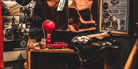 Cluttered room with various items such as a red lamp, toy cars, and framed posters on the walls.