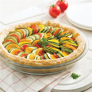 Colorful vegetable tart or quiche with sliced zucchini, tomatoes, and other vegetables arranged in a pie crust