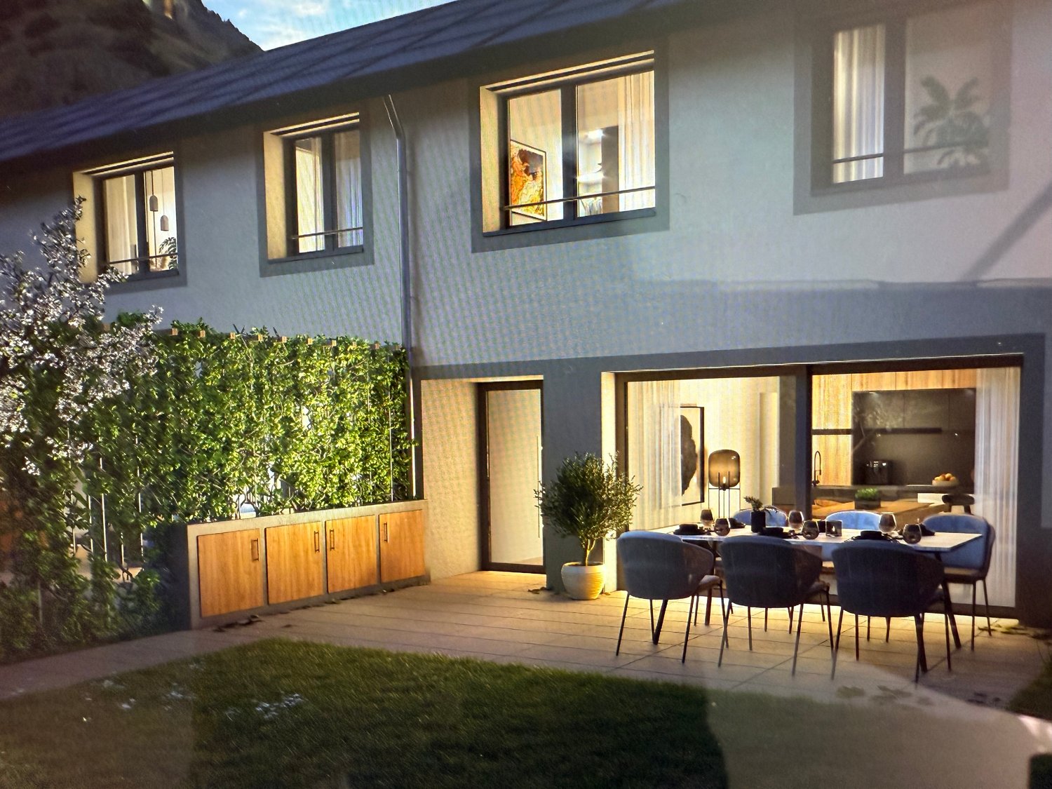 2 story house, gray walls, wooden doors, large windows, dining table with chairs in terrace, potted plants