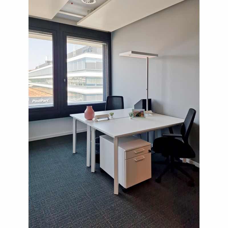 small office with large windows, two chairs, white desk, a lamp, filing cabinet, black office chair