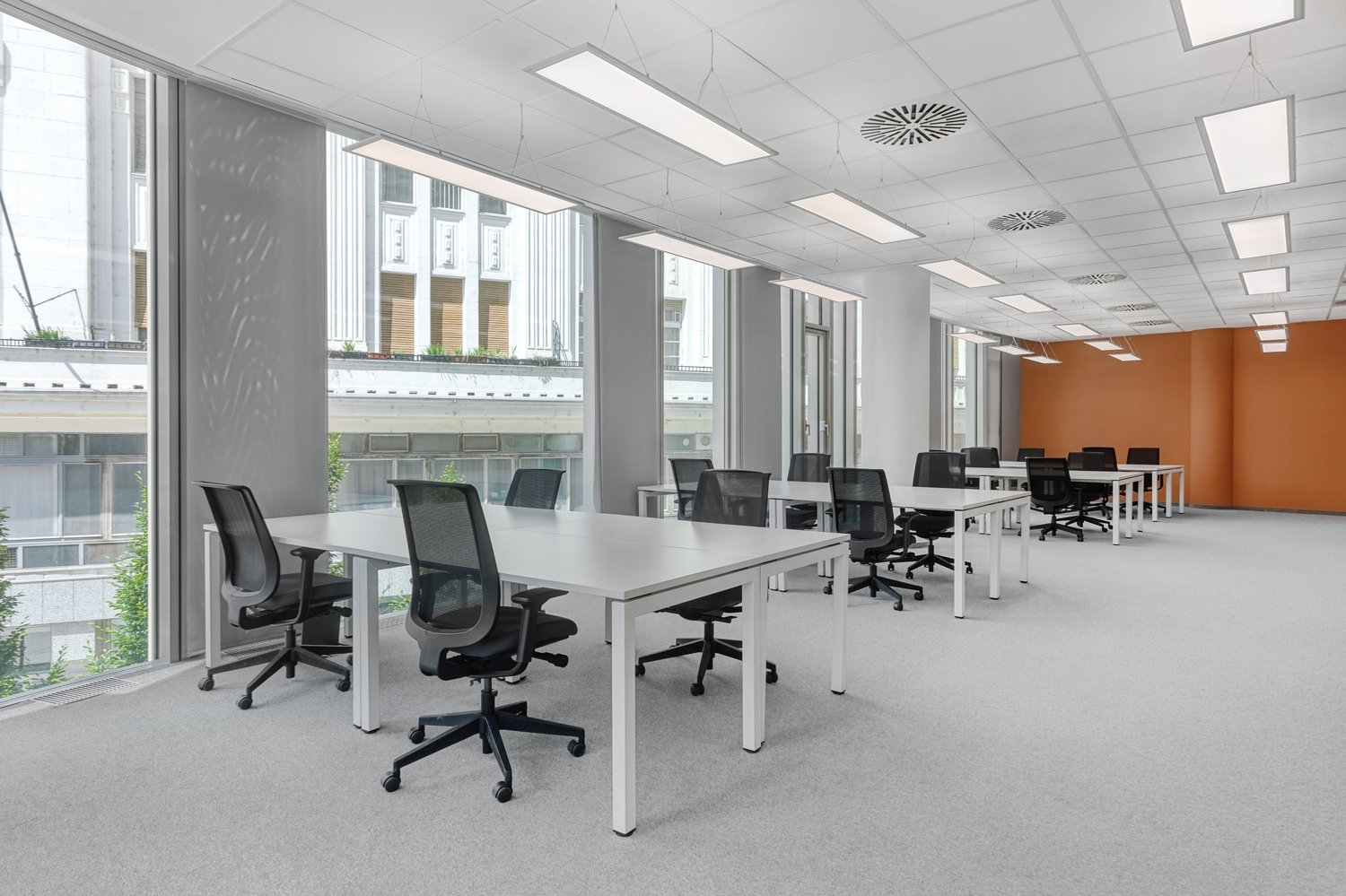 open floor plan, white desks, black chairs, windows, modern design, minimalistic