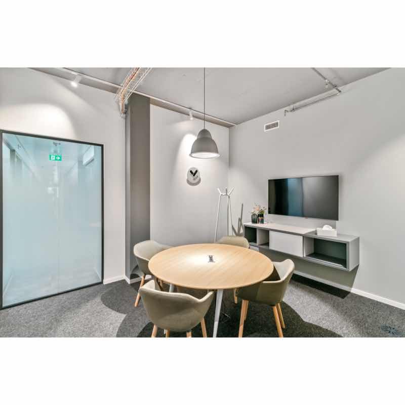 modern meeting room with round table, chairs, TV, and a glass door