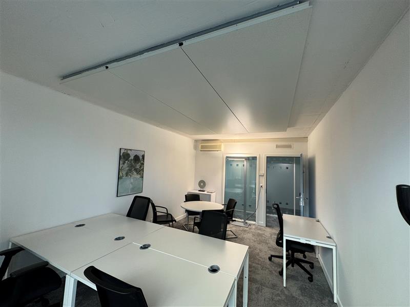 empty room, white walls, white desks, black chairs, round table, picture on wall, glass doors