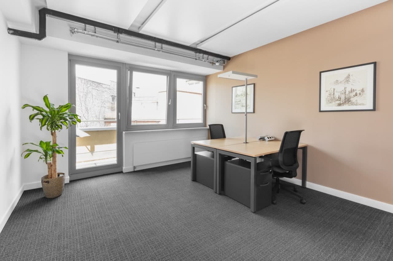 empty office room with desk, chairs, and windows