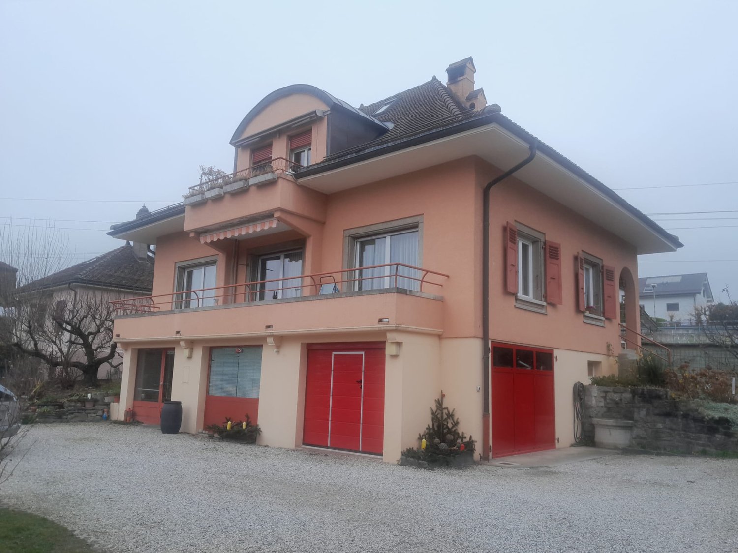 2 story house, red garage doors, balcony, gravel driveway
