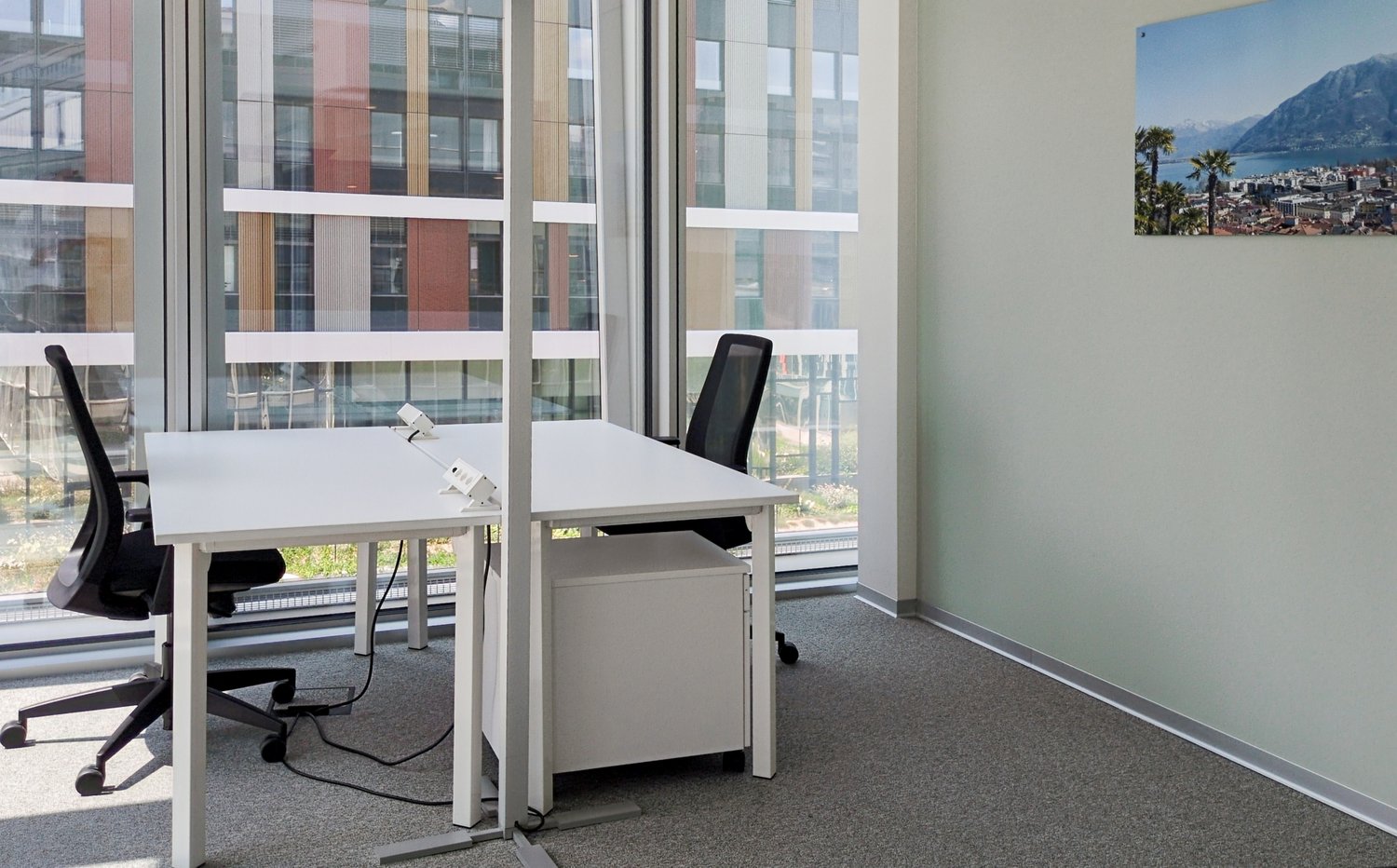 Office desk area with two chairs, glass doors, white walls, and a view of the city.