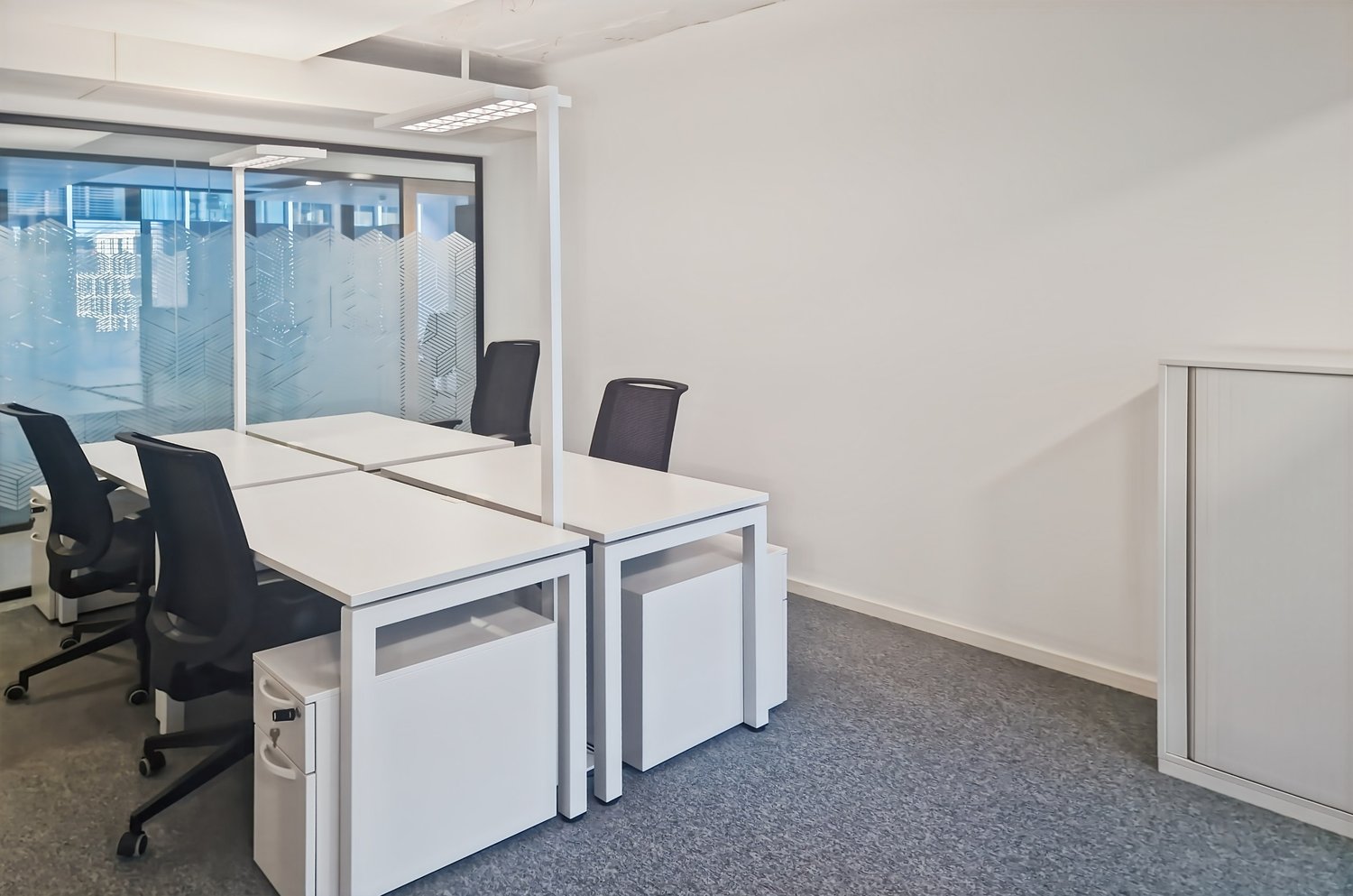 modern office with white desks, black chairs, glass wall, white walls, gray floor