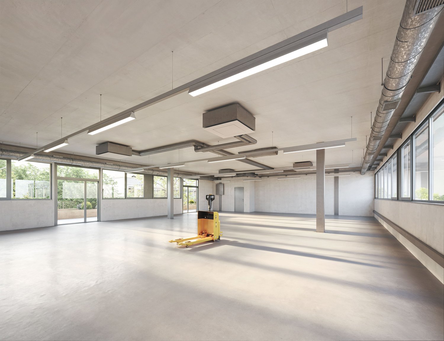 Large open commercial space with concrete floors, exposed ceiling, and large windows. The space is equipped with overhead lighting fixtures and a yellow pallet jack in the center of the room.