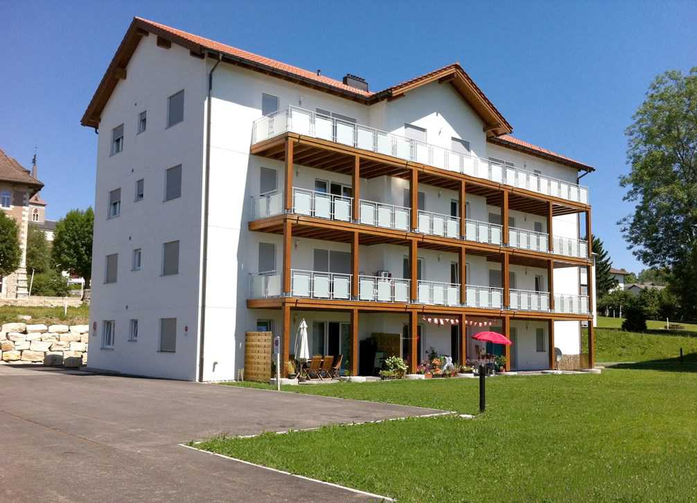 white exterior, balconies, red roof, grassy area, outdoor seating