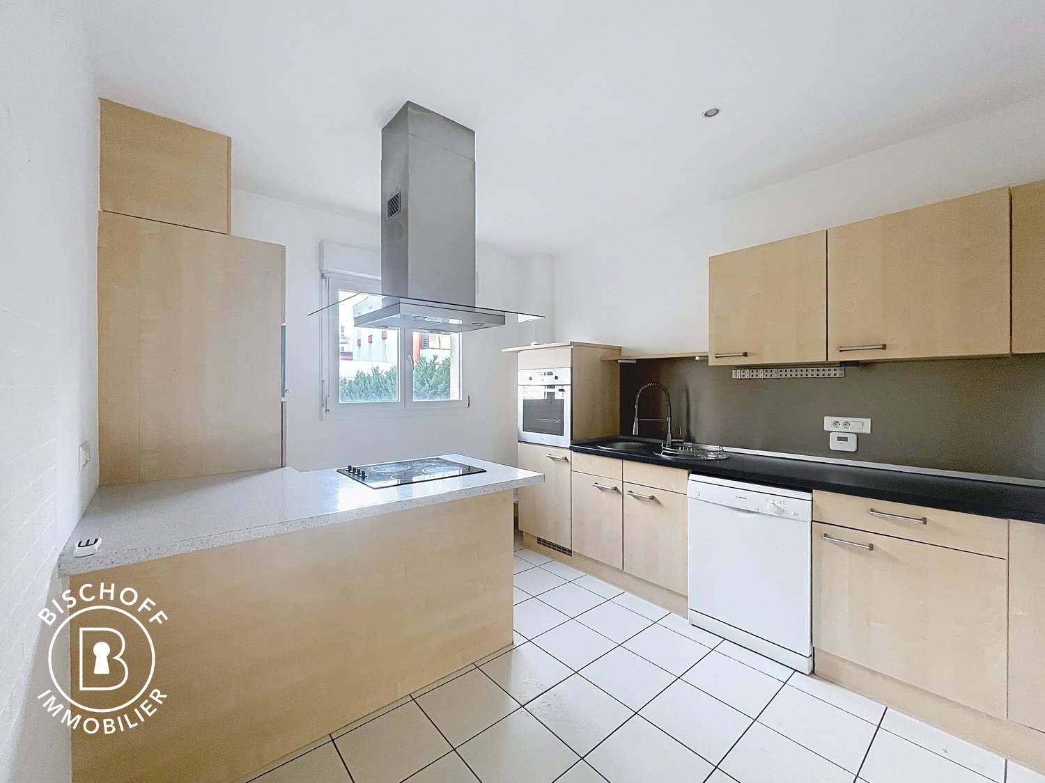 Open plan kitchen with granite countertops, built-in appliances including a dishwasher and oven, stainless steel appliances, white tile flooring, wooden cabinets, a central island with a gas stovetop and extractor hood, and a window allowing natural light