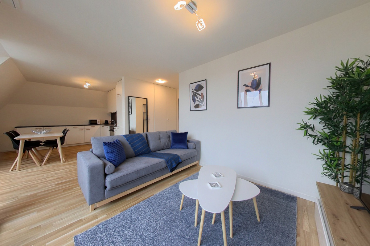 open-plan living room with kitchen, large windows, dining table, sofa, tables, plants