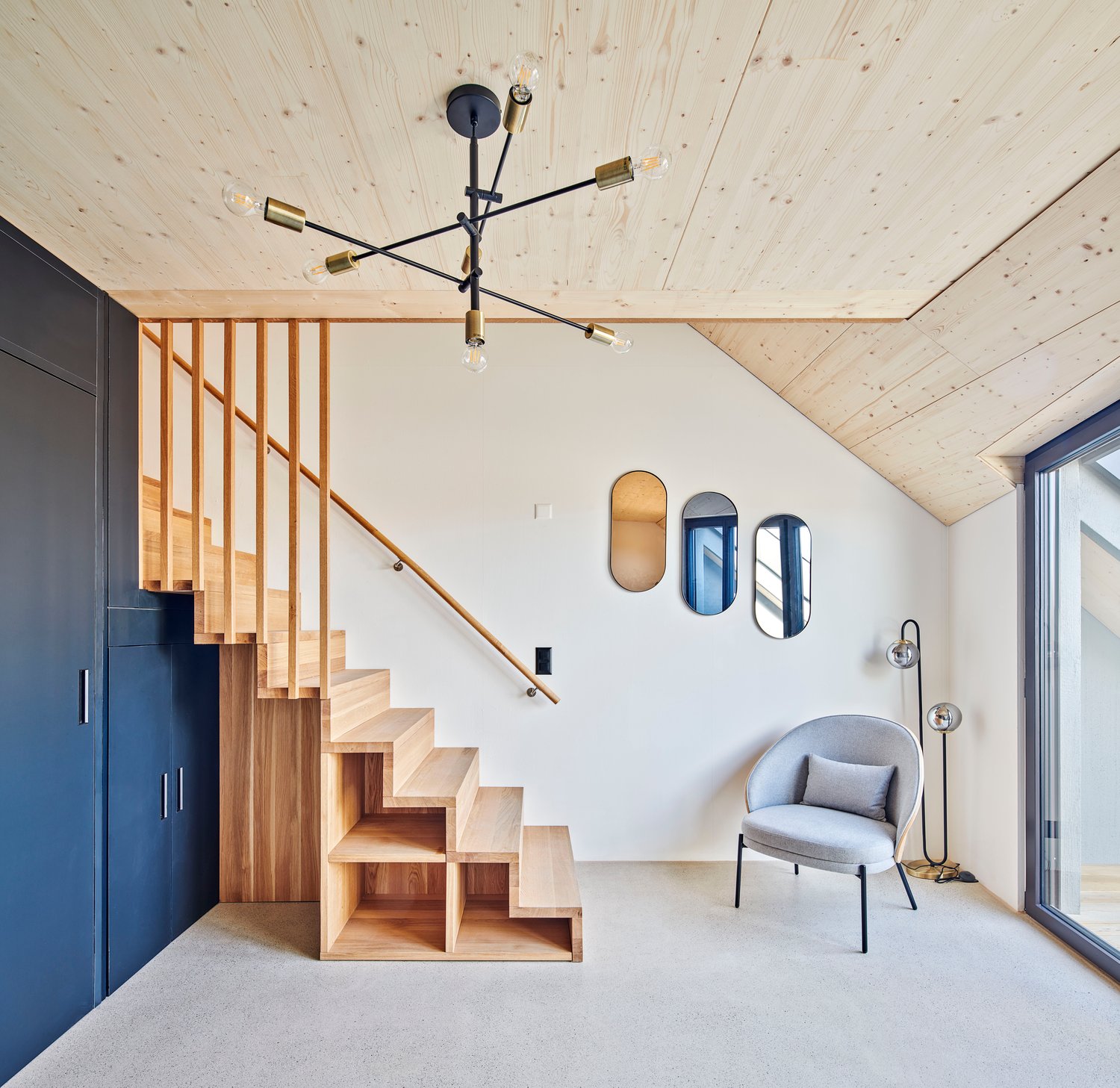 wooden staircase, white walls, gray chair, wooden shelves, mirrors, lamp