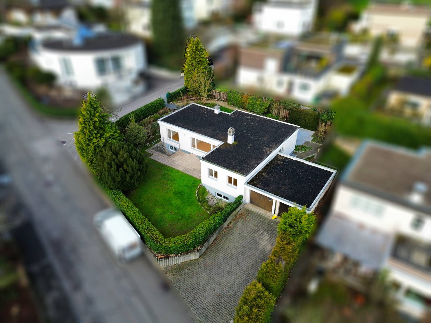 Detached house, single story, white walls, brown garage, paved driveway, garden, hedges, green grass, asphalt road