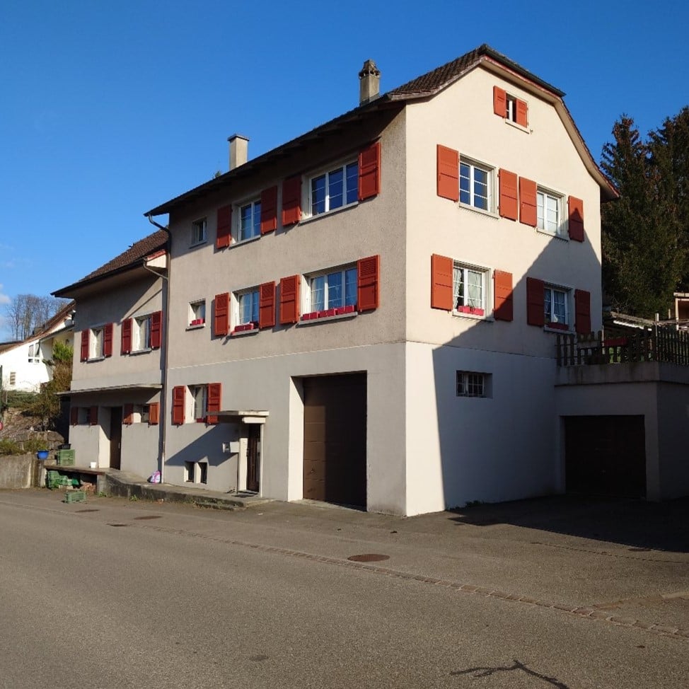2 story house, white walls, brown roof, red shutters, 2 garages, windows with flower boxes