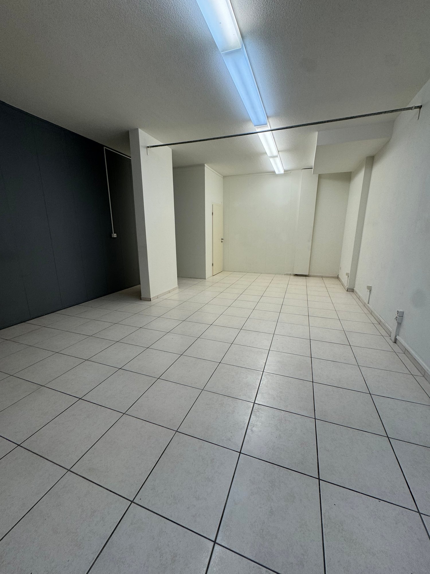 empty room, white tiles, white walls, ceiling lights, door, power outlets