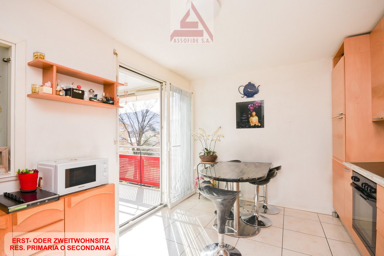 white wall, white floor, wooden cabinet, glass door, table and chair, balcony, microwave, potted plant