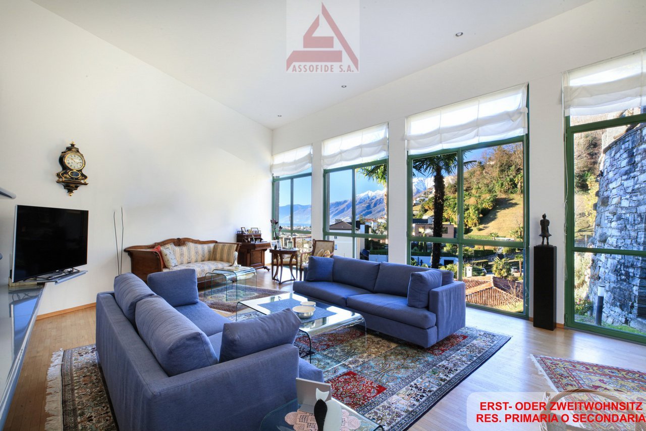 large windows, blue couches, glass coffee table, TV stand, clock, statue, carpet, large windows with mountain views