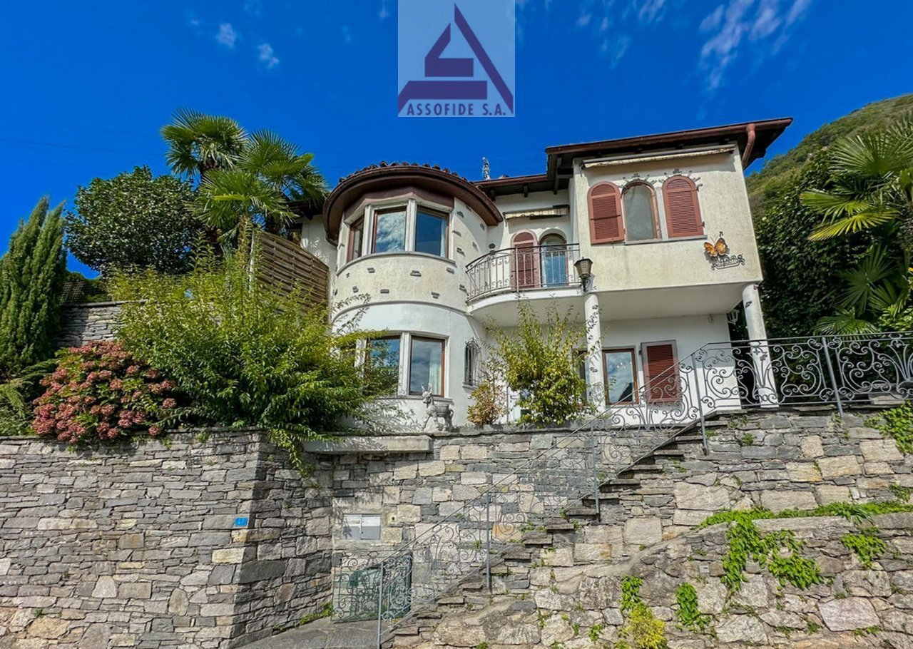 Two-story house, stone wall, balcony, arch windows, statue on top of the wall