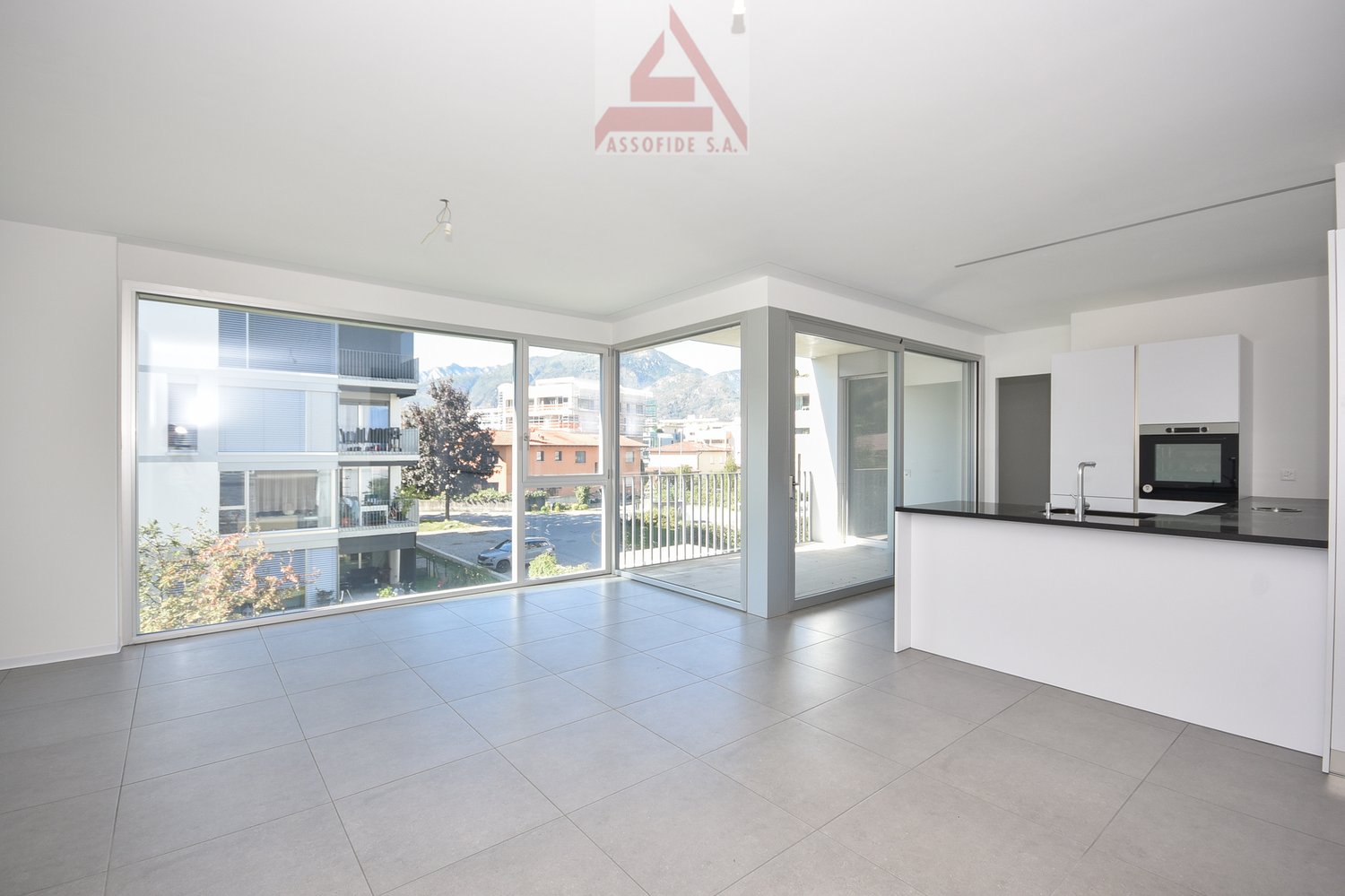 Open kitchen, glass doors leading to terrace, large windows, tiled floor