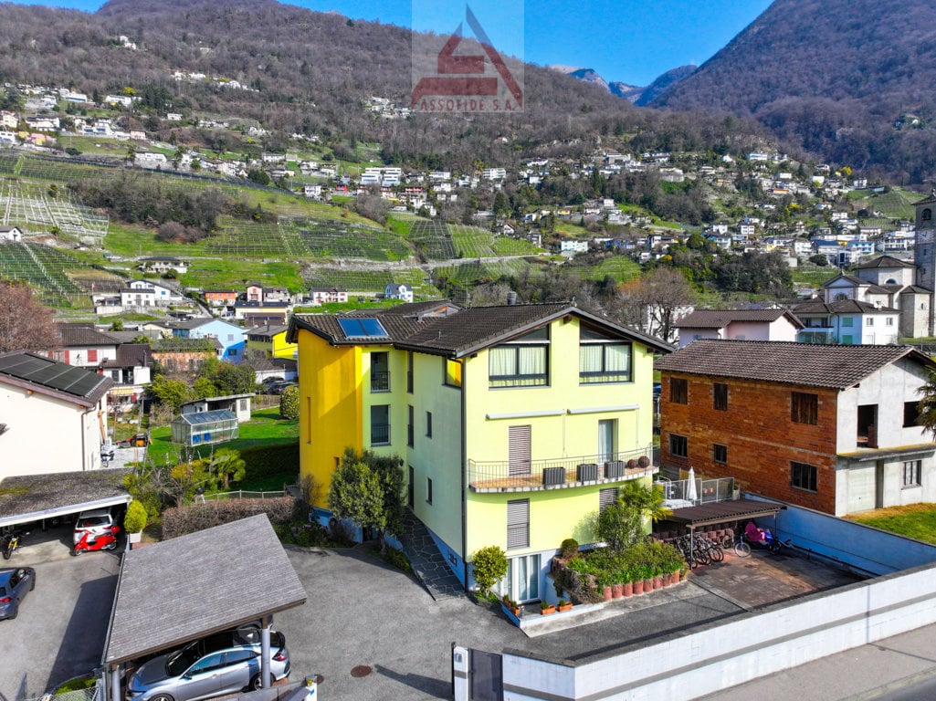 Large multi-story building, yellow paint, balcony, mountain view
