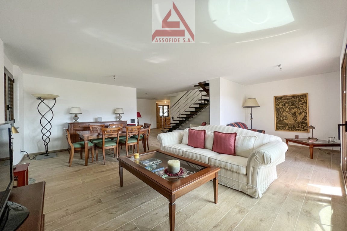 living room with wooden floor, white couch, wooden coffee table, dining table, wooden chairs, wooden cabinet, lamps, painting, TV