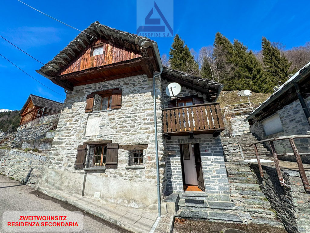 Stone house, wooden balcony, multiple windows, satellite dish, wooden shutters, stone wall
