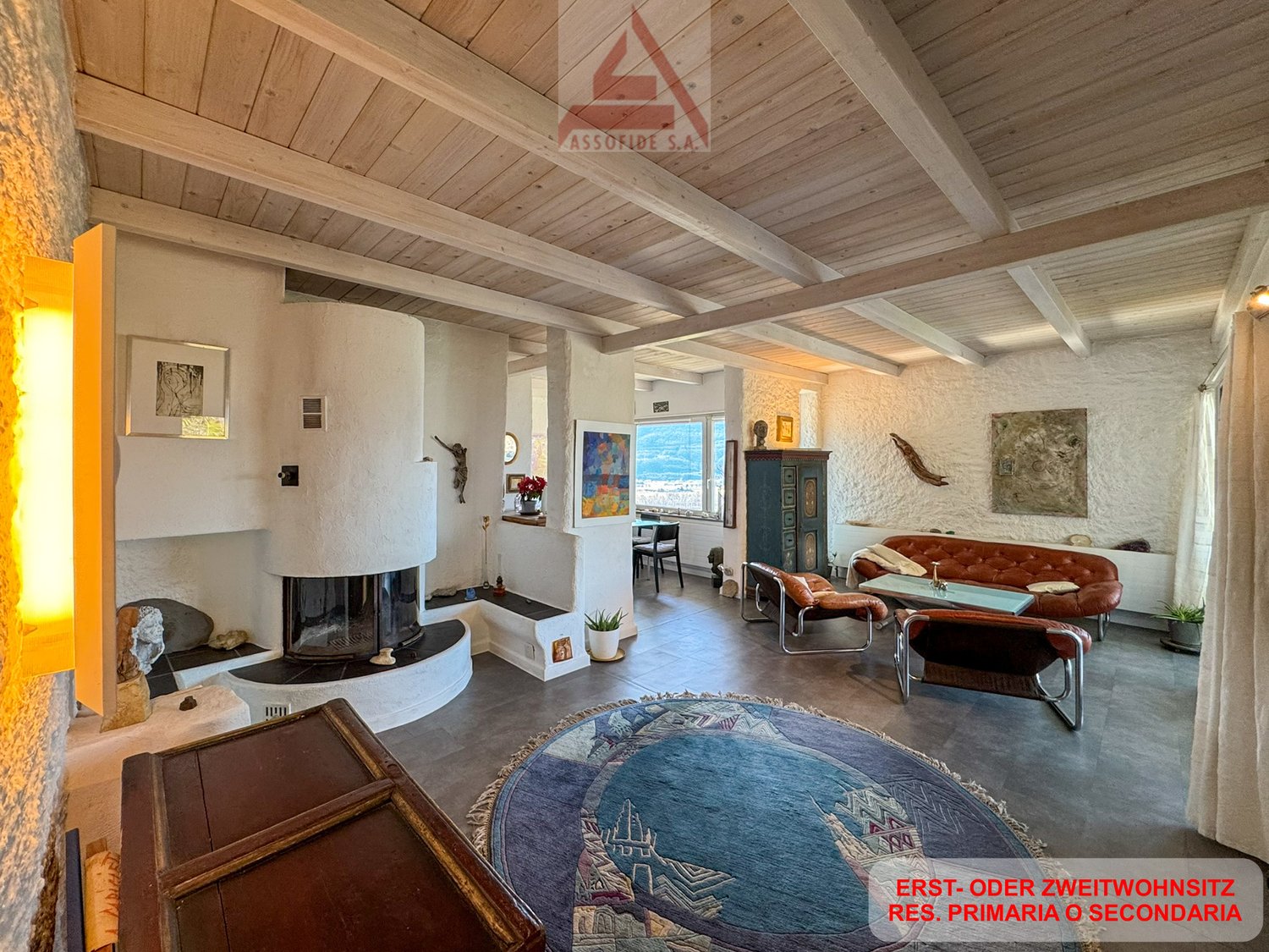 wooden ceiling, fireplace, large windows, couch, armchairs, rug, side table, artwork