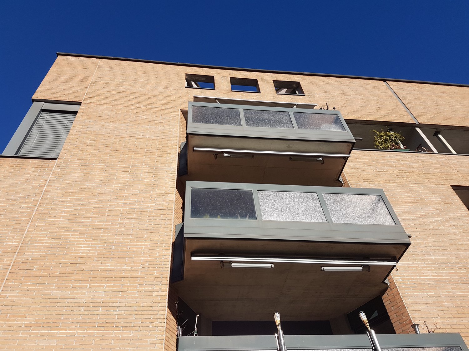brick facade, multiple balconies, blue sky, large windows