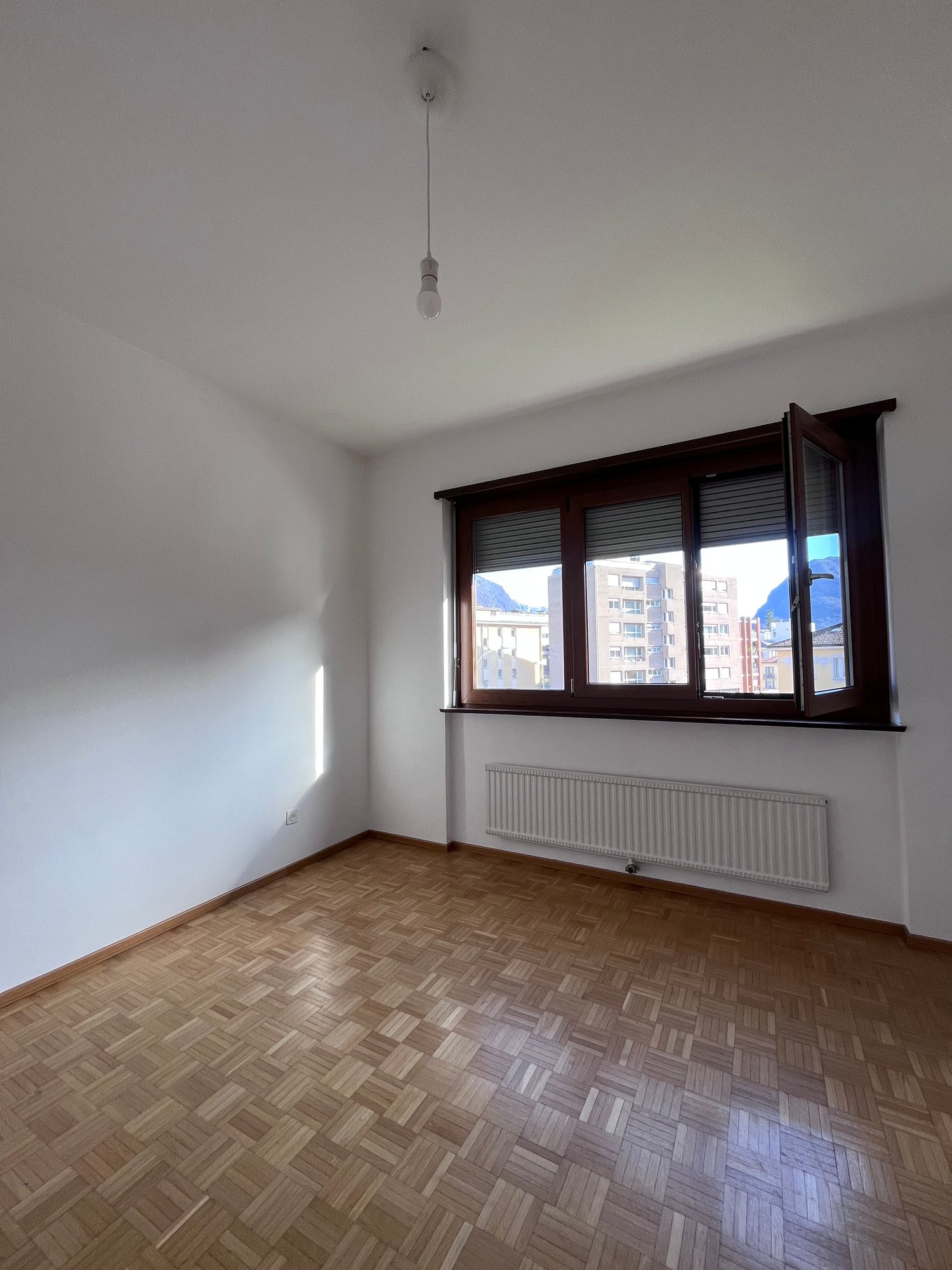empty room, wooden floor, white walls, large window, radiator, open window