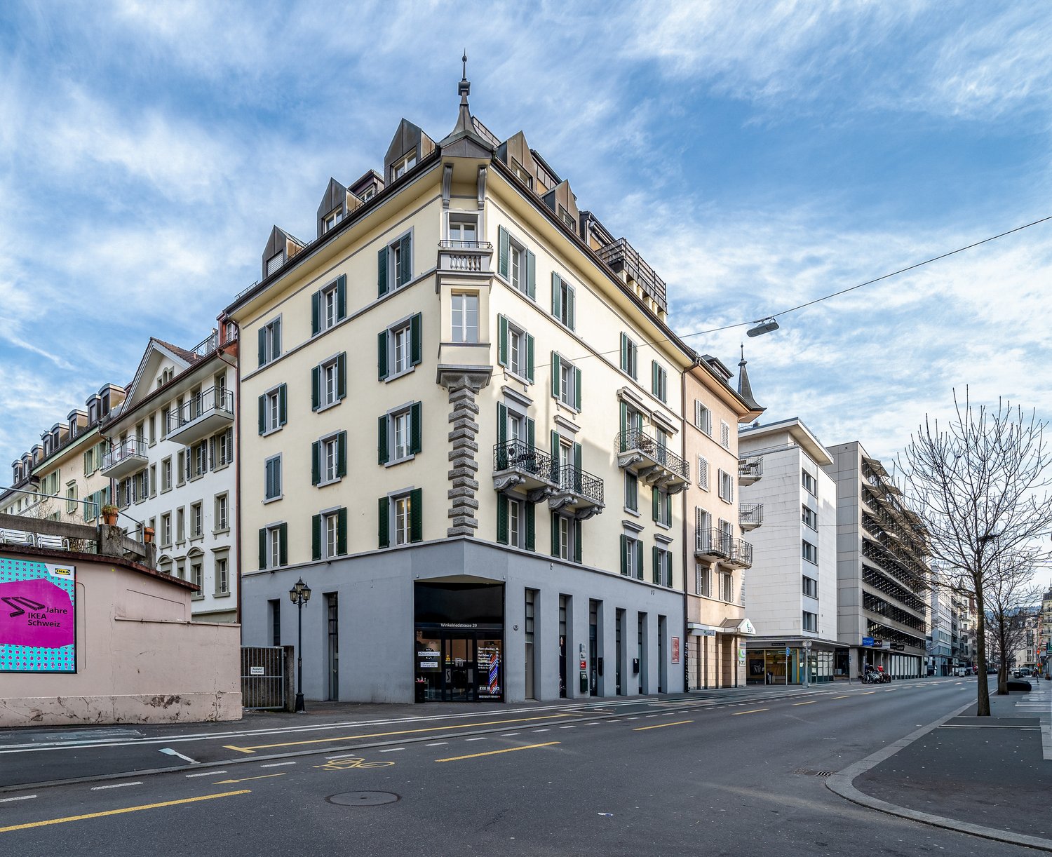 5 story building, beige and white facade, green shutters, balconies, street level shops