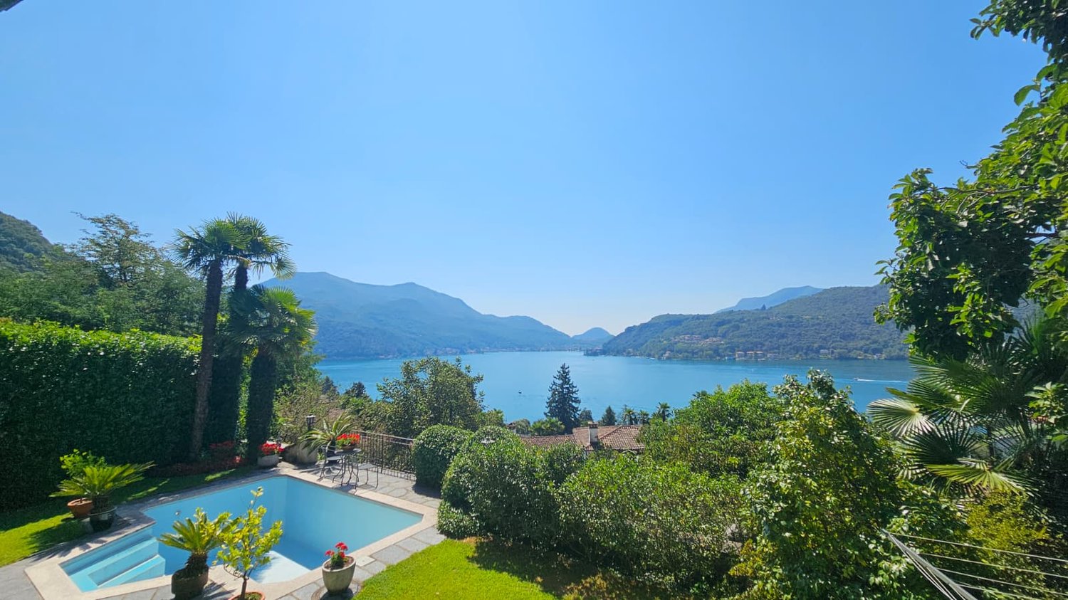 Pool with a lake view, greenery, a table with chairs