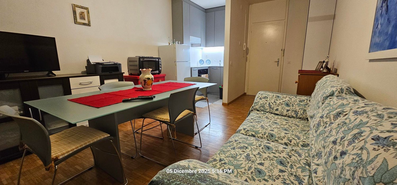 Table with 4 chairs, couch, microwave, refrigerator, flat screen TV, kitchen area