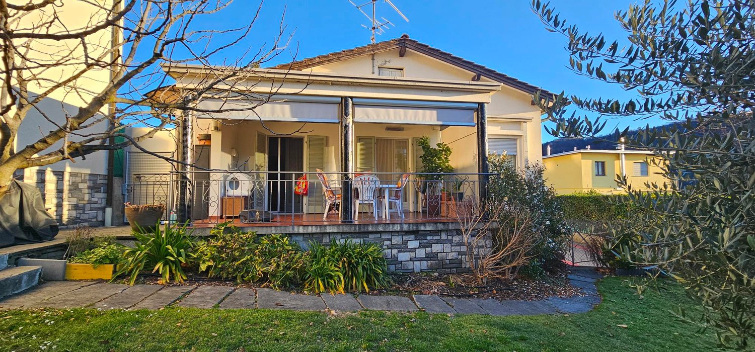 single-story house, porch with retractable awning, wooden floor, railings, chairs, table, outdoor plants