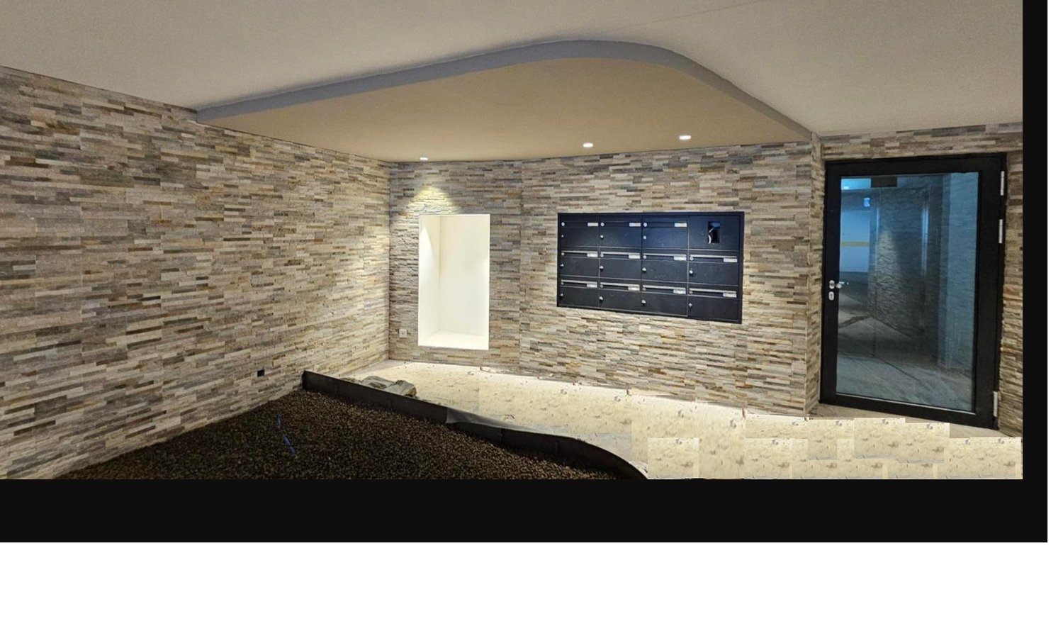 brick wall, glass door, black mailbox, room with a black rug