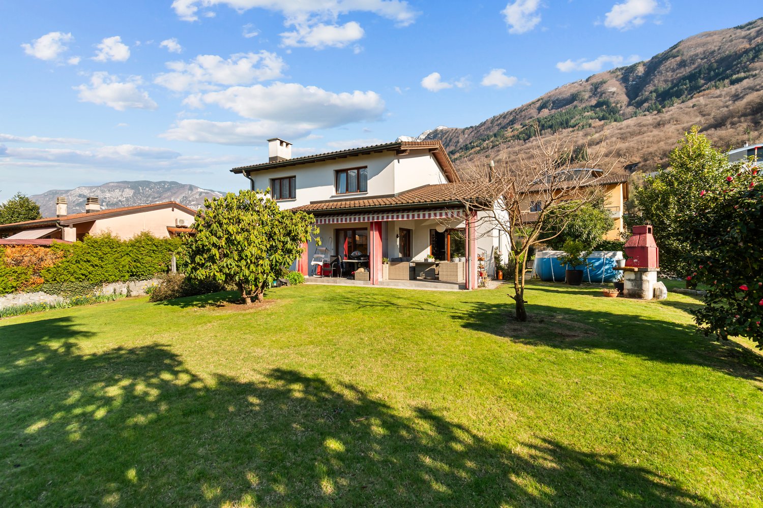 2 story house, white exterior, brown roof, large lawn, trees, mountains in the background