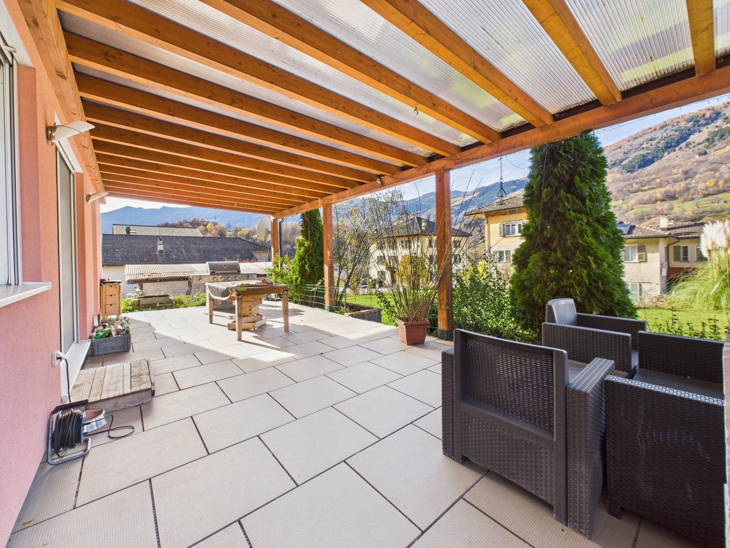 covered terrace, wooden pergola, outdoor table, chairs, plants, grill, tiled floor