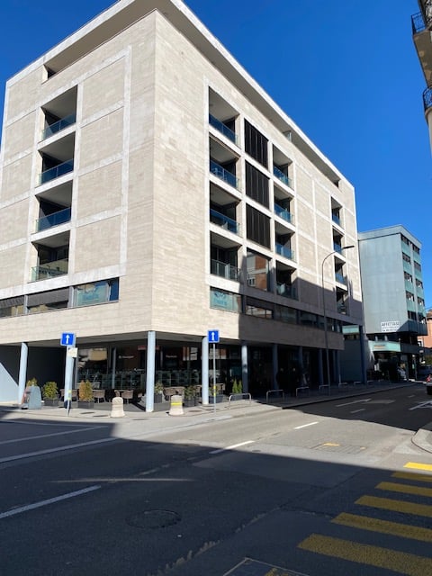 Modern building with multiple floors, balconies, and a ground floor with a restaurant.