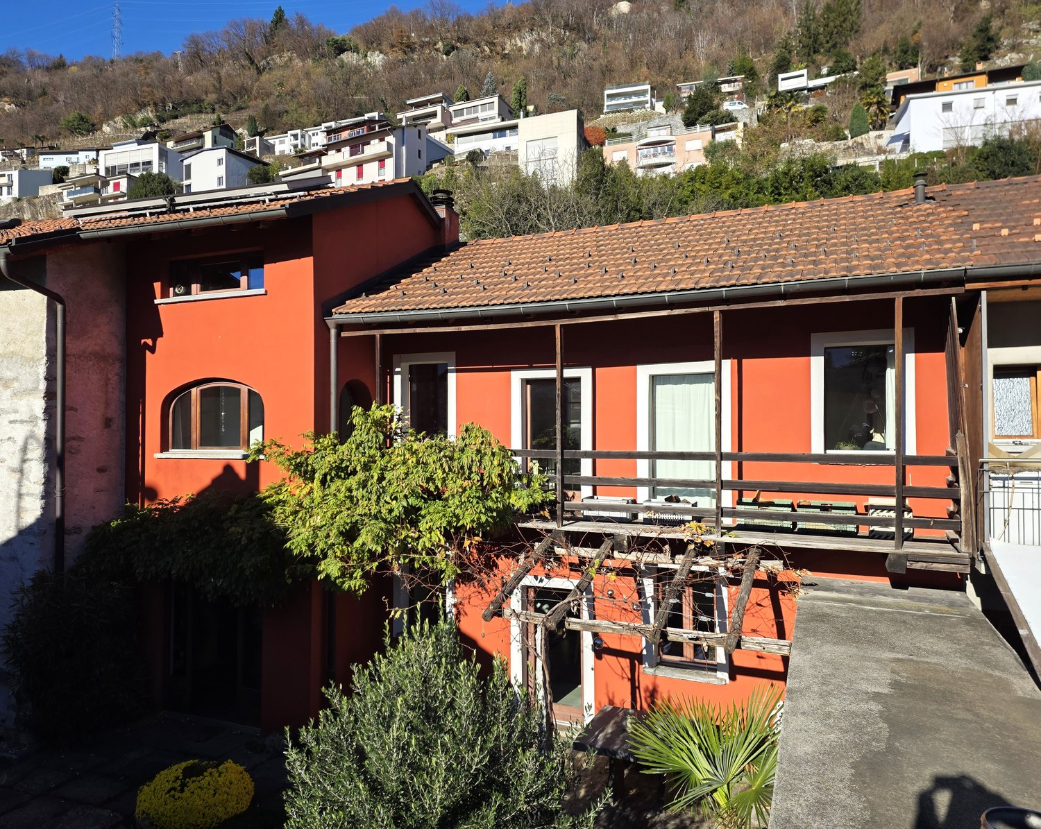 Terraced house, red brick walls, wooden balcony, windows with white frames, solar panels on the roof