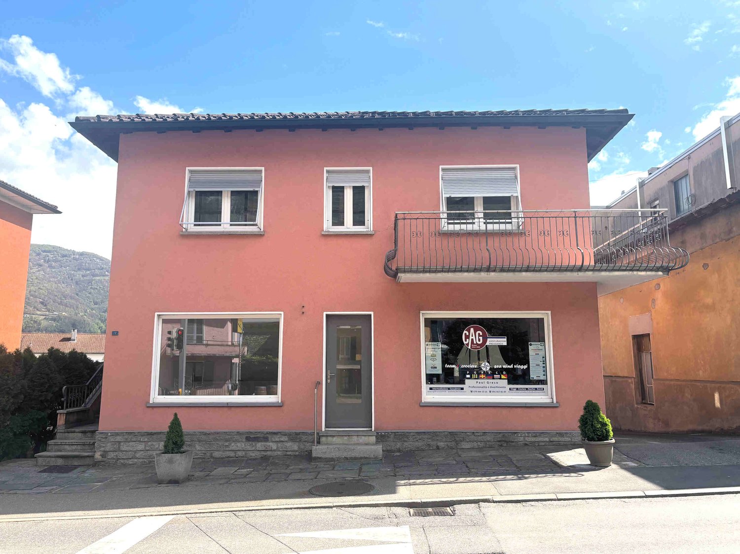 2 story house, pink exterior, white windows, balcony, front door, 2 small plants