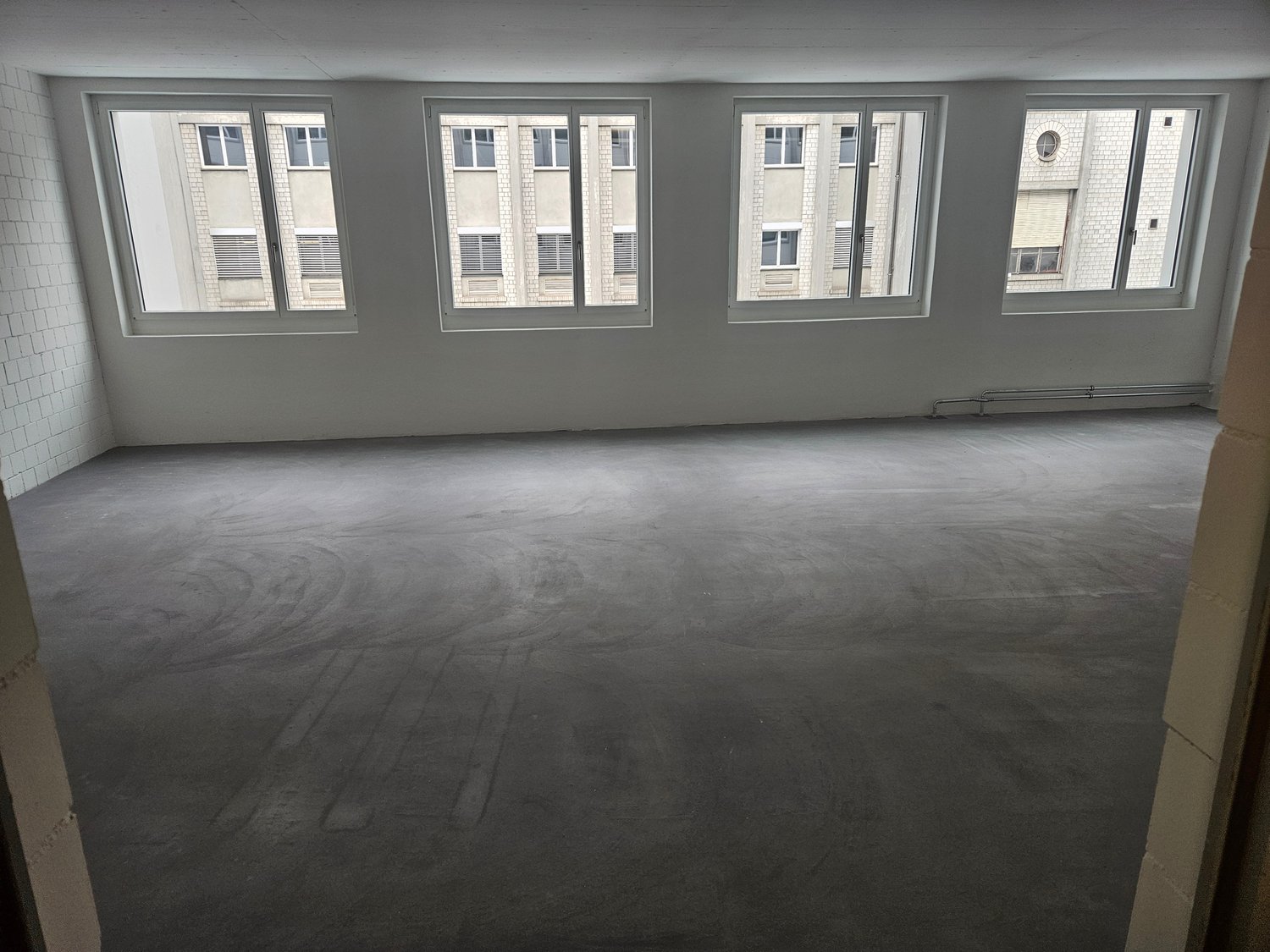 Empty room with 3 windows, concrete floor