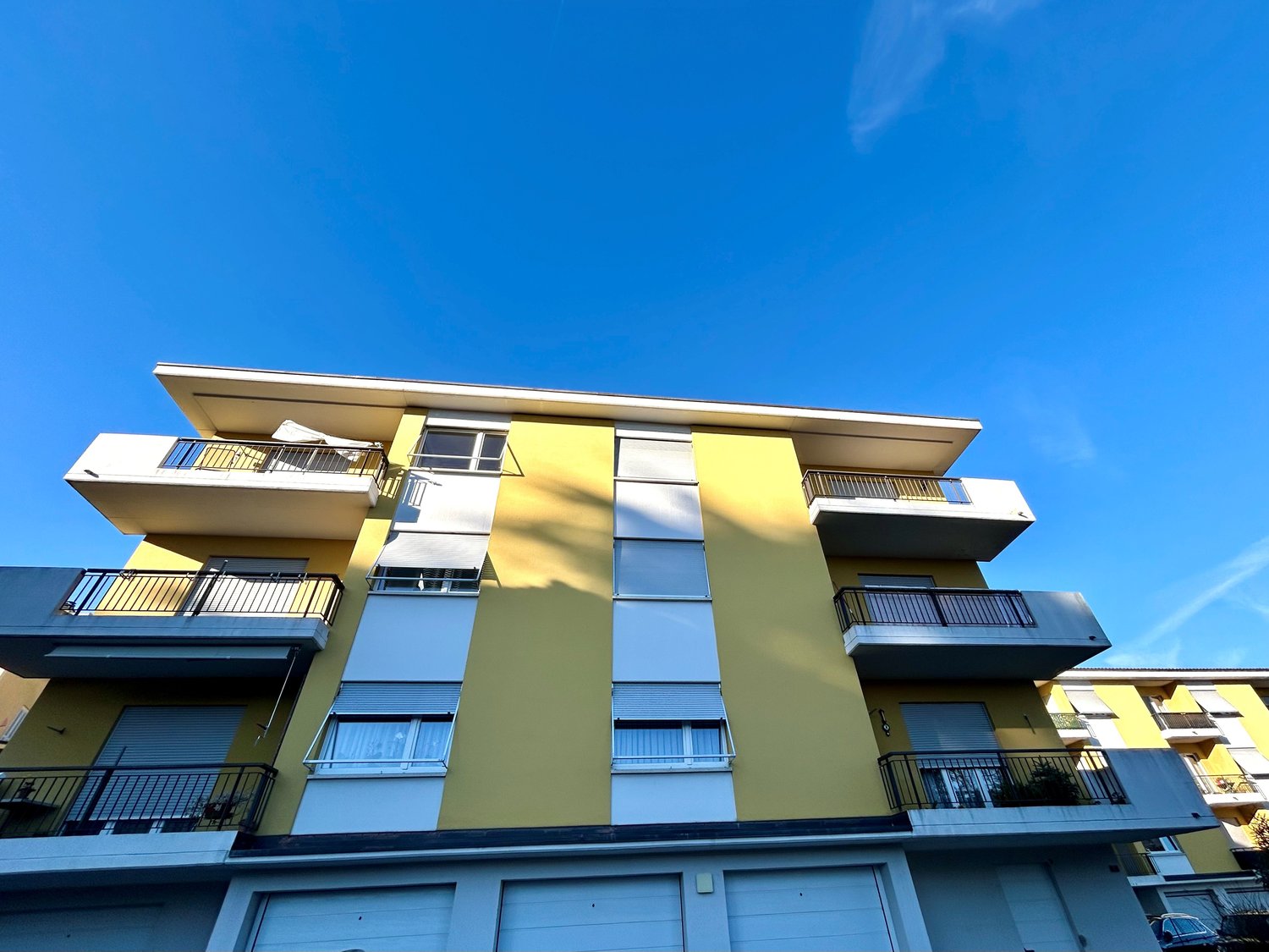 4 story building, yellow and white exterior, multiple balconies, garage