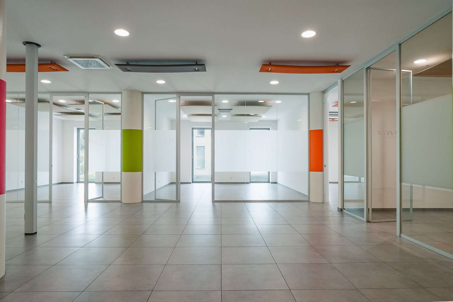 Wide hallway, tiled flooring, glass walls, no furniture visible
