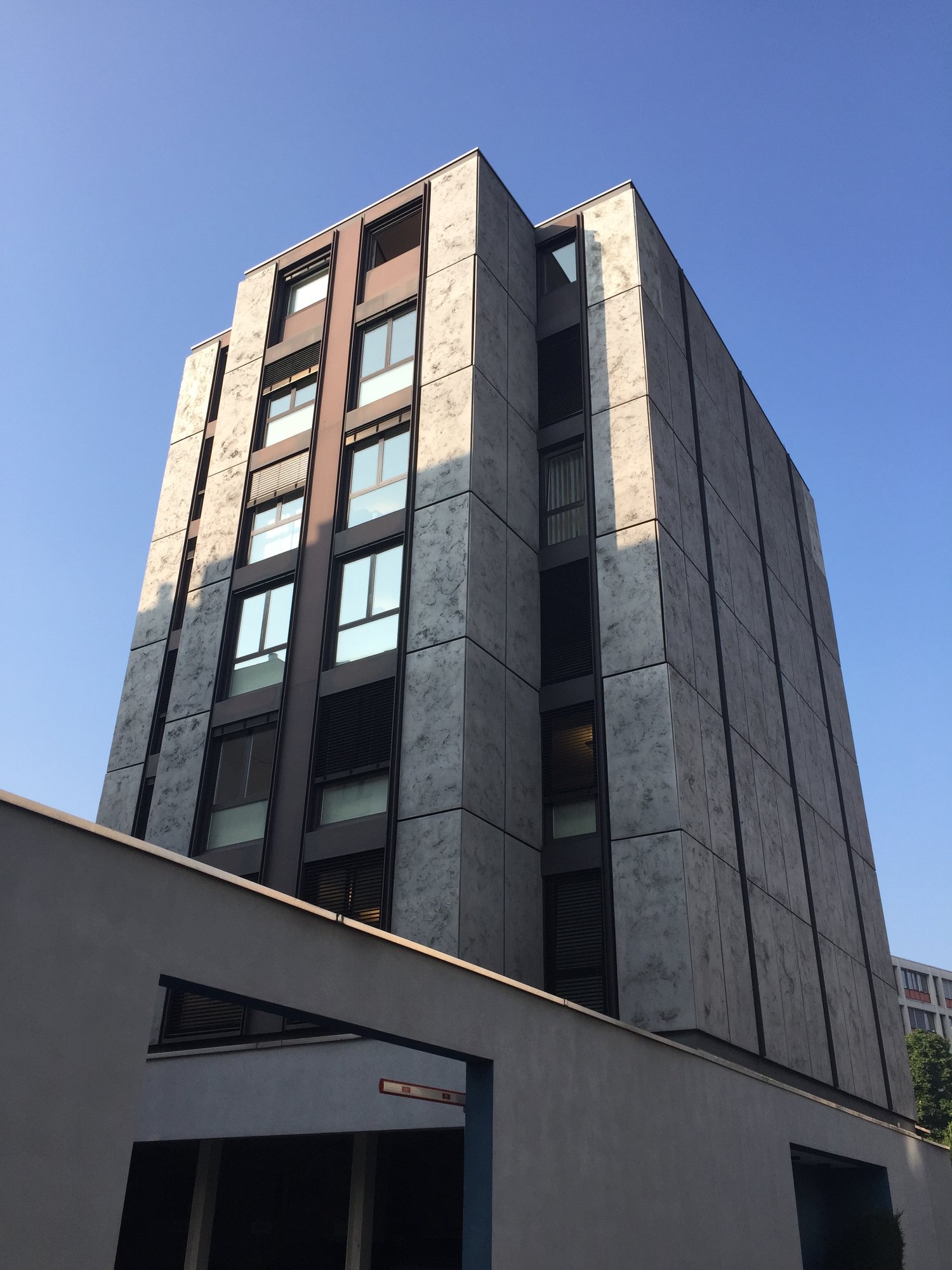 High-rise building, grey stone walls, multiple windows, ground floor with garage entrances