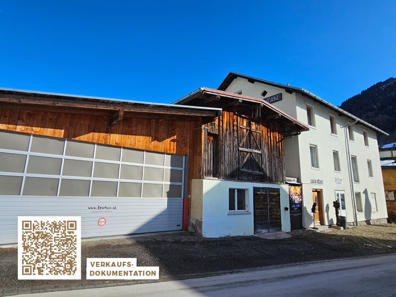 2-story building, white and wooden exterior, large garage, multiple windows, street-facing entrance
