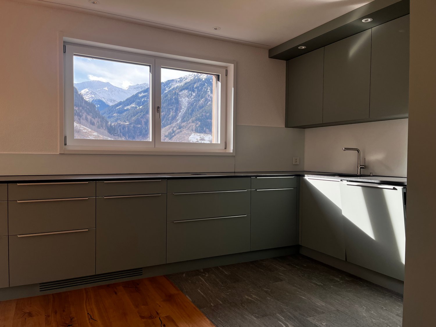 modern kitchen, gray cabinets, black countertops, window with mountain view, sink with faucet