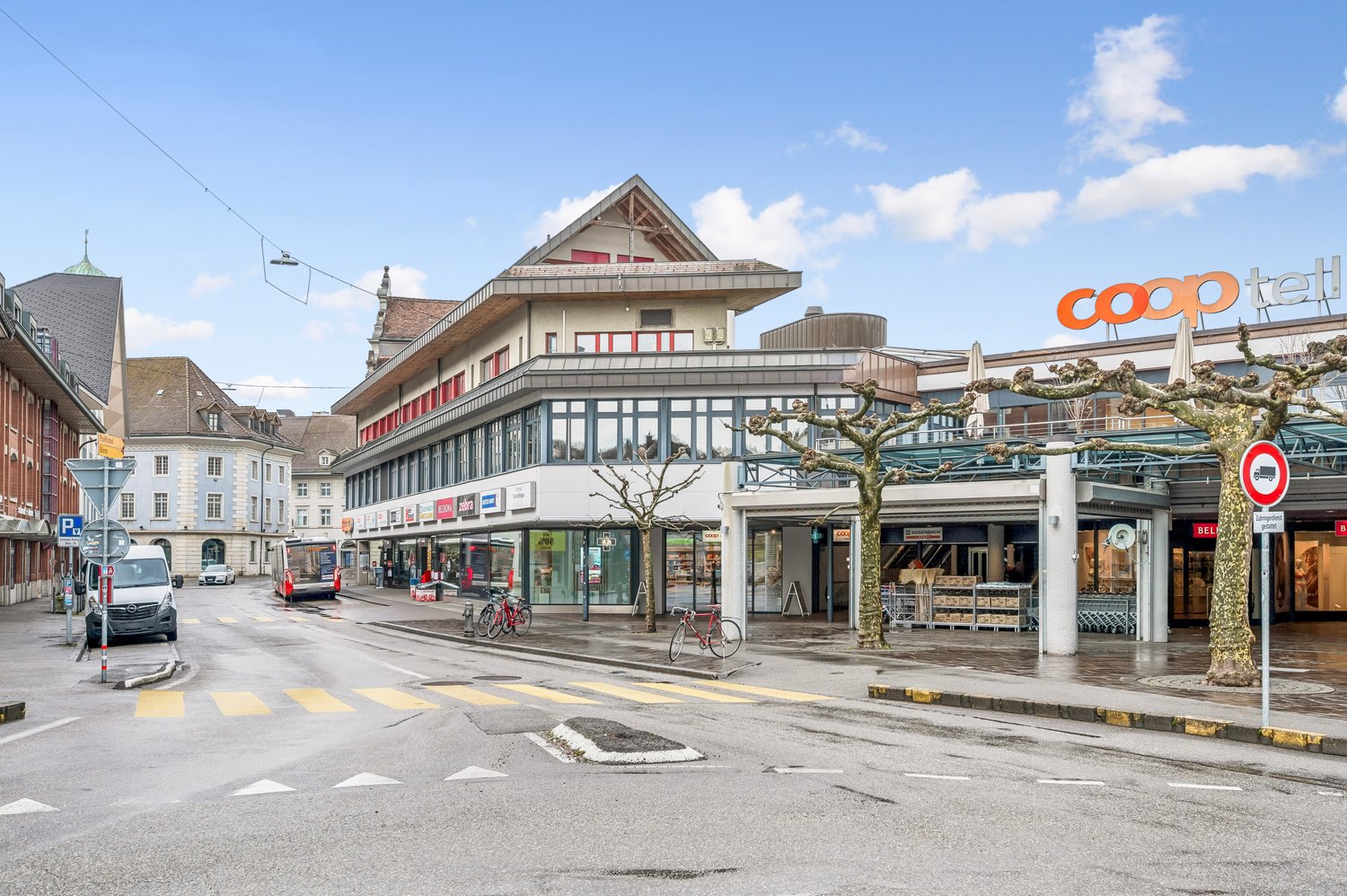 A multi-story building with glass windows and entrance, located on the side of the road, featuring a large sign reading 'COOP'