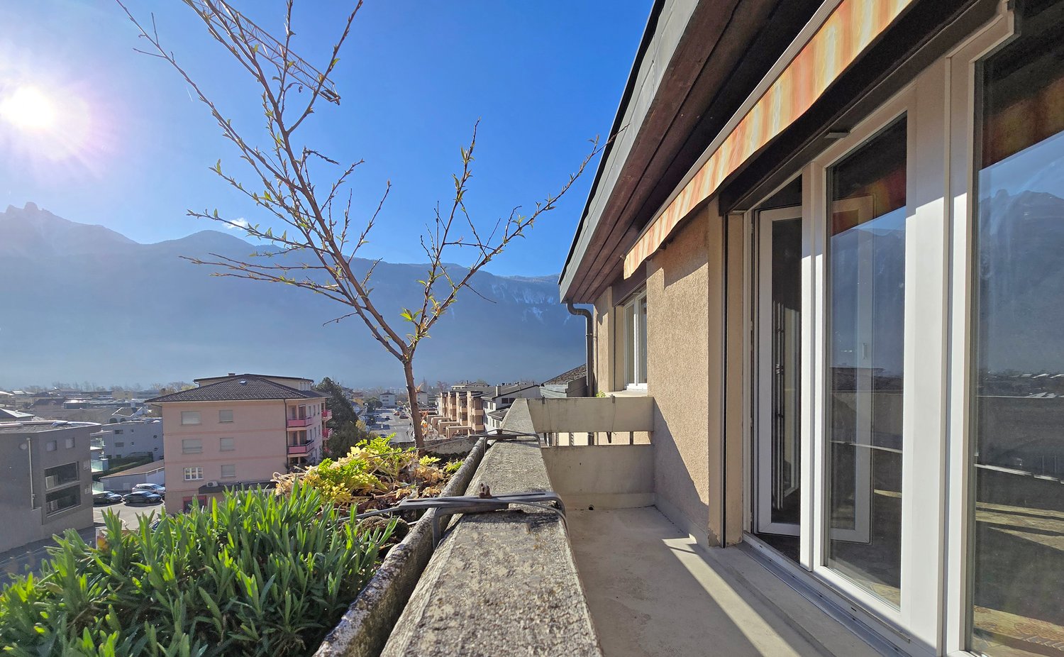 Building with balcony, plants, and a view of mountains
