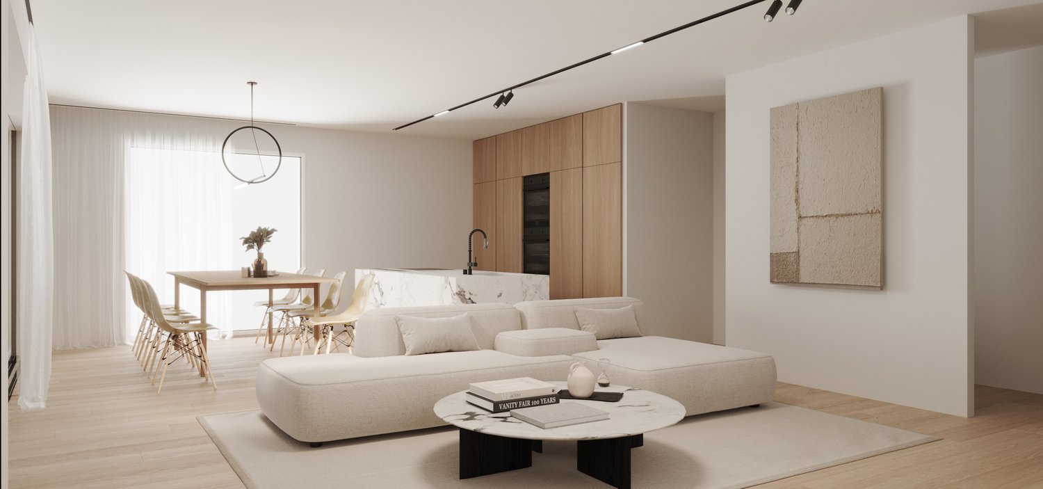 Spacious open-concept living area with a large white sectional sofa, round coffee table, and dining table with chairs. The kitchen features a marble countertop and built-in appliances. The room has a minimalist and modern design with neutral colors, wood