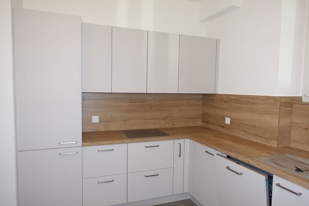 modern kitchen with white cabinets, wooden countertops, white drawers, a stove, and a sink